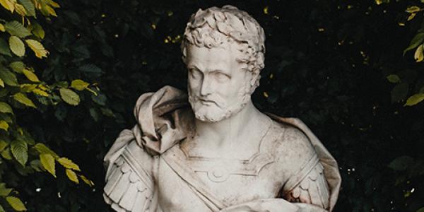 The bust of Marcus Aurelius in marble, sitting in a small garden.