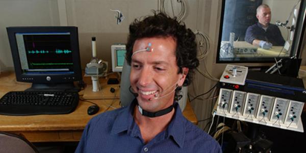 A man sits with research equipment surrounding to test its ability to change his hearing.