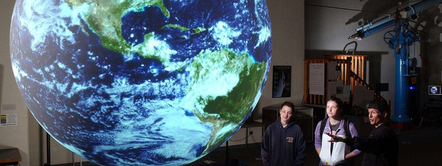 Onlookers observe a giant glowing globe at Fiske Planetarium