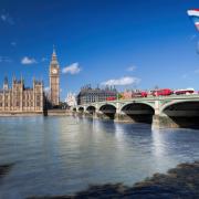Stock image of double decker red buses on a bridge with Big Ben clock tower in the background