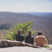 three people sitting down overlooking mountains