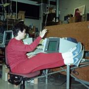 Woman in red track suit puts her feet up while working on a desktop computer