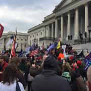 Crowd waving flags amasses in front of the U.S. Capitol building