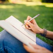 Woman seated in grass writing in journal